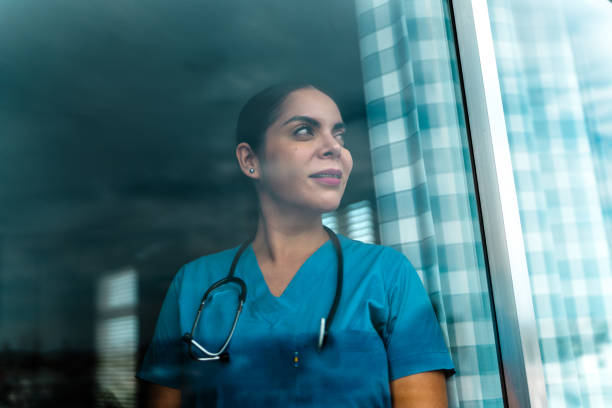 istock Female nurse contemplating looking through window 2163493481