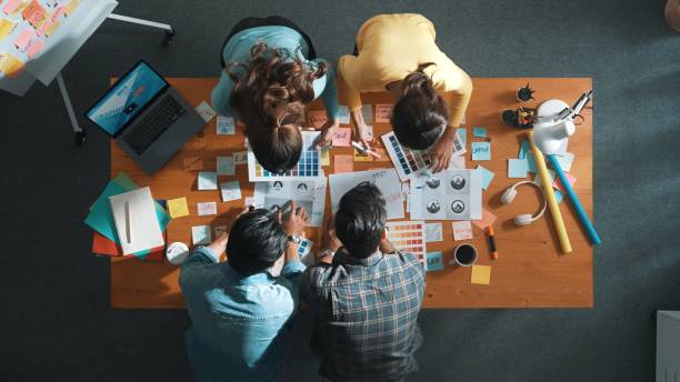 istock Top view of skilled designer holding logo while discussing with team. Symposium. 2163493539
