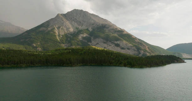 Sunset over lake and mountains with storm clouds above, Crowsnest Lake, Canadian Rockies