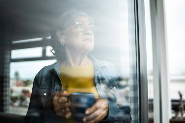 istock Senior woman contemplating while look through window at home 2163495343