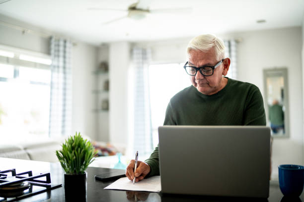 istock Portrait of a senior man using computer and doing home finances at home 2163495351