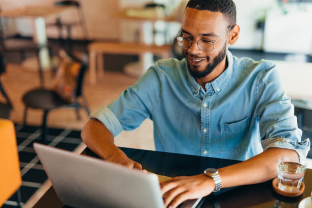 istock Young man sitting in coffee shop and using laptop 2163495637