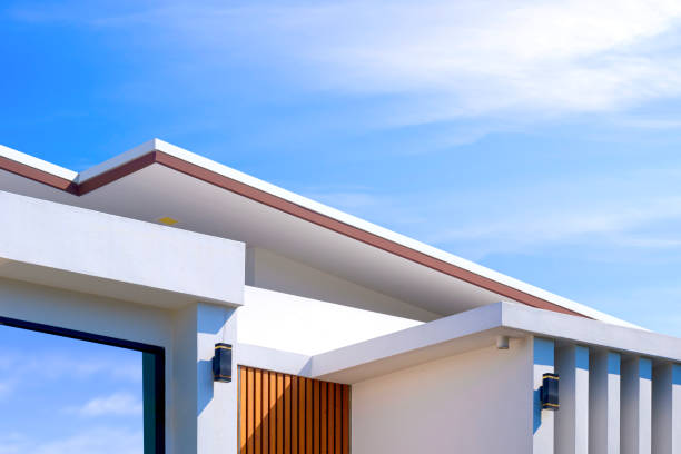 Modern house building with sunlight on geometric pattern surface of white concrete wall against blue sky background