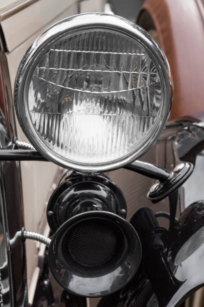 Close up of red classic car front headlight and grill.