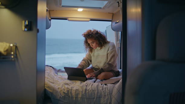 istock Serious freelancer working camper van looking laptop at evening. Woman surfing 2163510689