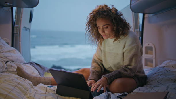 istock Remote worker surfing camper van looking laptop at evening. Woman freelancer 2163512066