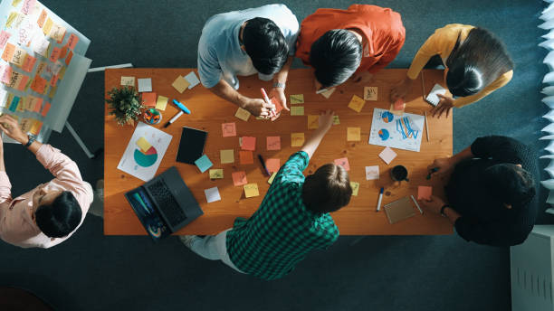 istock Top view of diverse team writing sticky notes to brainstorm idea. Convocation. 2163512867