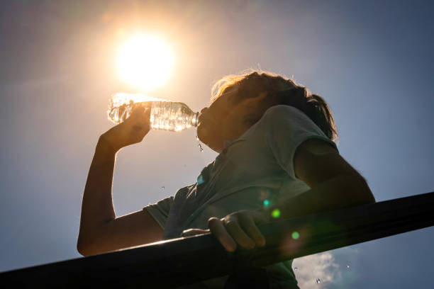 Boy drinking water from a bottle on a sunny hot day.