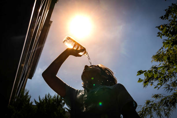 Boy drinking water from a bottle on a sunny hot day.