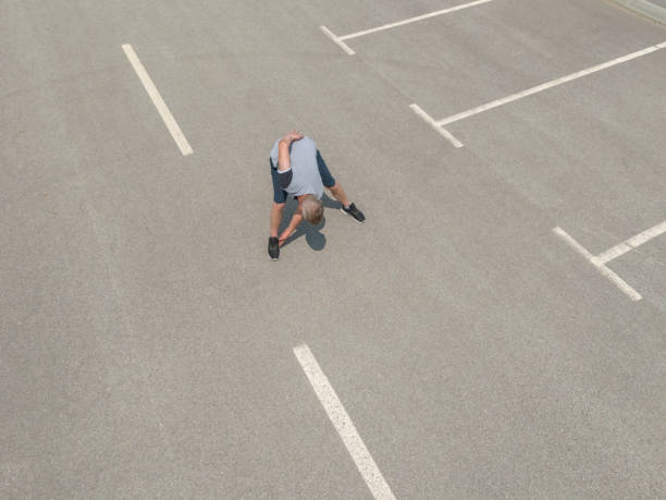 Active man exercising - stretching outdoors on car parking in the city