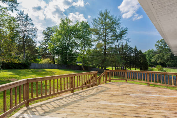 istock Spacious Wooden Backyard Deck With Green Lawn And Trees Under Clear Sky. 2163515735