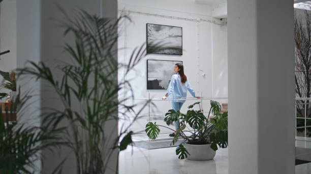 istock Thoughtful woman looking paintings on wall. Focused visitor watching artwork 2163517395