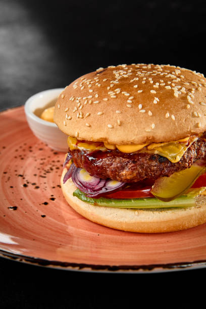 istock Juicy Beef Burger with Fresh Vegetables and Sauce on a Rustic Plate 2163519623