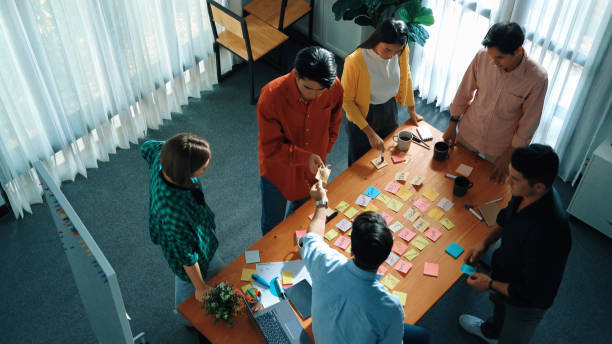 istock Top view of diverse people writing and stick sticky notes at board. Convocation. 2163520979