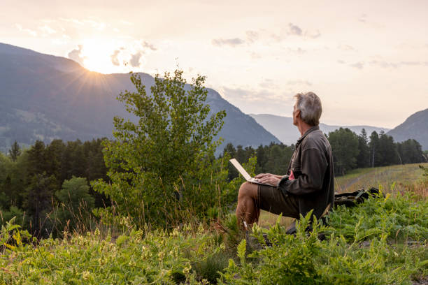 istock Mature man uses laptop in mountain meadow 2163522697
