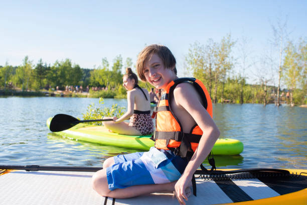 istock 11 year old boy is boarding on a lake, on SUP, Stand up paddle board 2163523140