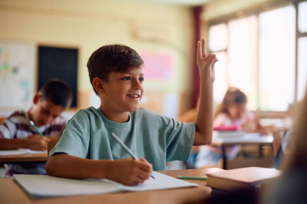 istock Happy boy raising his hand during a class at school. 2163524016