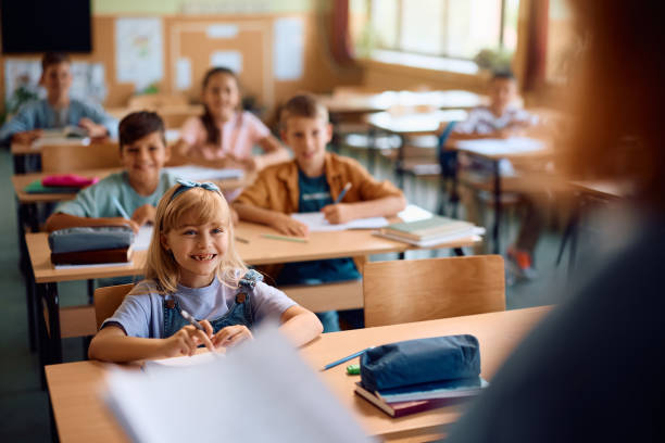 istock Group of elementary students listening to their teacher during a class in the classroom. 2163524038