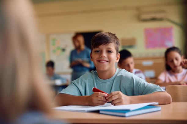 istock Happy schoolboy having a class in the classroom and looking at camera. 2163524062