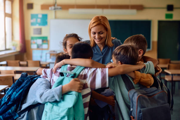 istock Happy teacher and her students embracing while greeting on first day of school. 2163524077