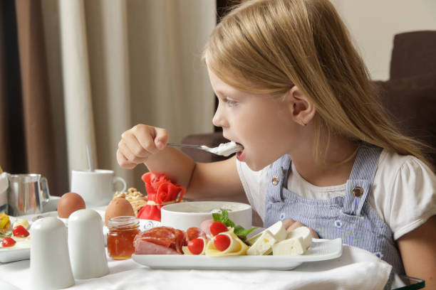 Cute little girl having breakfast, cereals with yogurt, tasty and healthy choice between various dishes served on the table
