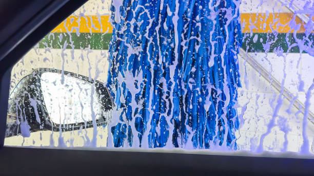 Soap and brushes cleaning a car window during an automated wash.