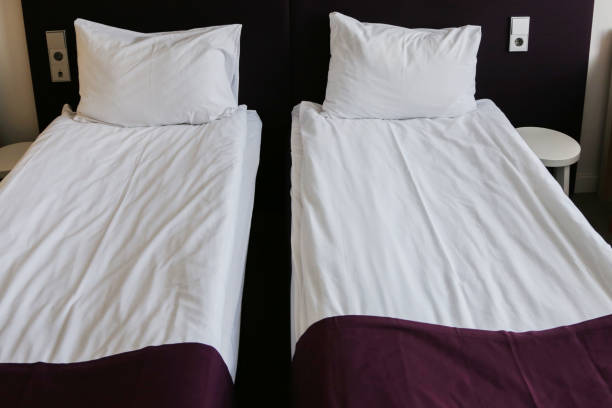 istock Two neatly made beds in a hotel. 2163526643