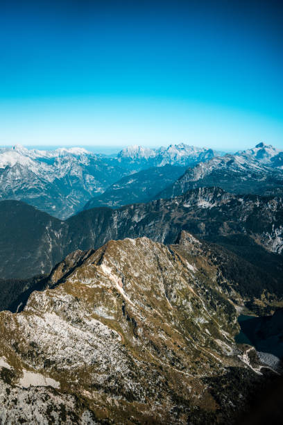 High angle shot of rugged mountain peaks and valleys seen from the window of an aircraft, highlighting nature's grandiosity and the experience of a panoramic flight.
