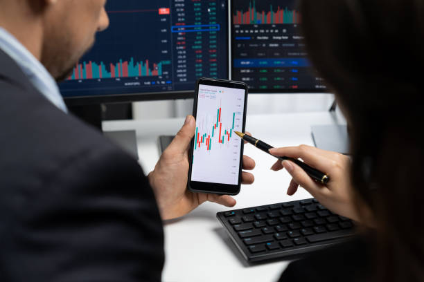 istock Focusing phone with discussing stock market in two business traders. Postulate. 2163528620
