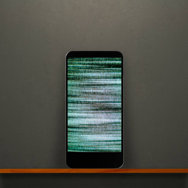 Close-up of grainy screen smart phone on a wooden shelf against dark concrete wall.