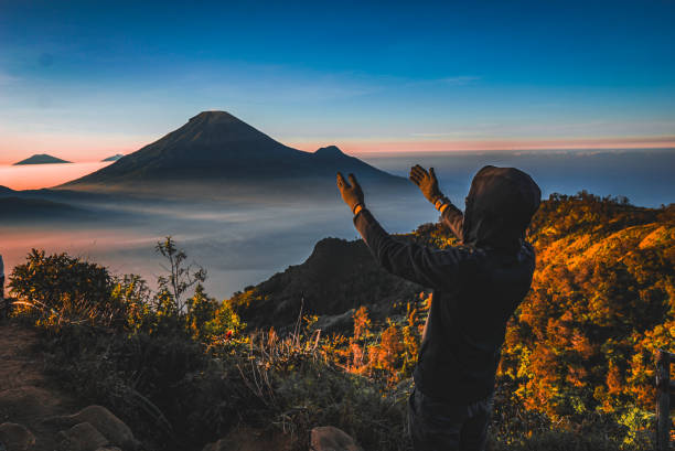 istock The image captures a trekker, his arms extended, perched atop a mountain. 2163536740