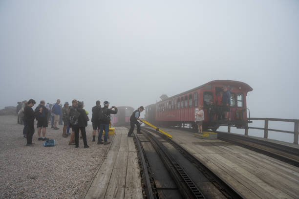 People getting out  COG train at the top of Mount Washington during summer day while others are waiting to get in