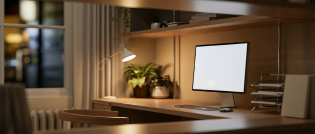 istock A computer mockup on a wooden table, illuminated by a table lamp in a home office workspace at night 2163537563