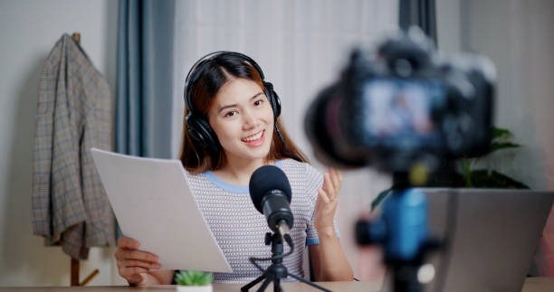 istock Young woman host making podcast at her small studio. Camera is recording her while she speaks and smile 2163538598