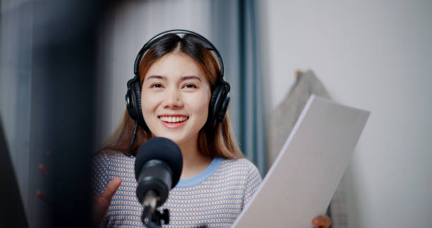 istock Young woman host making podcast at her small studio. Camera is recording her while she speaks and smile 2163538606