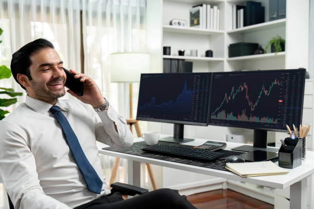 istock Trader calling to consultant or partner with two stock exchange screen. Surmise. 2163543450
