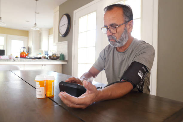 istock Latino Man Sitting At Table Checking His Blood Pressure 2163543730