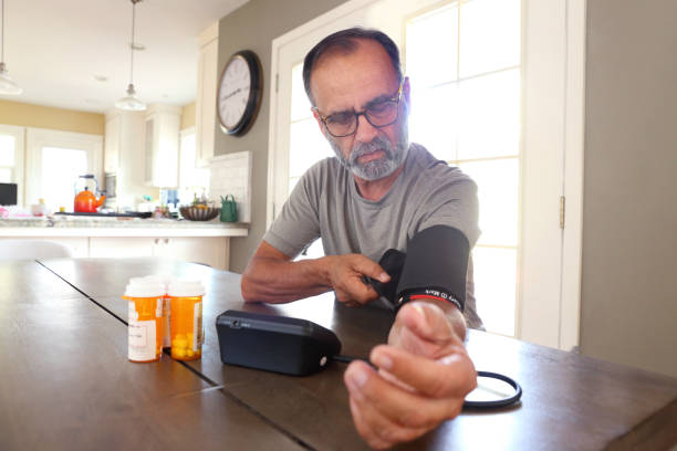 istock Latino Man Sitting At Table Checking His Blood Pressure 2163543736