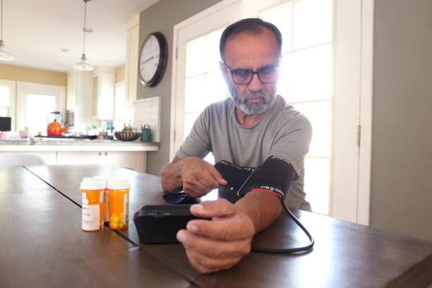 istock Latino Man Sitting At Table Checking His Blood Pressure 2163543750