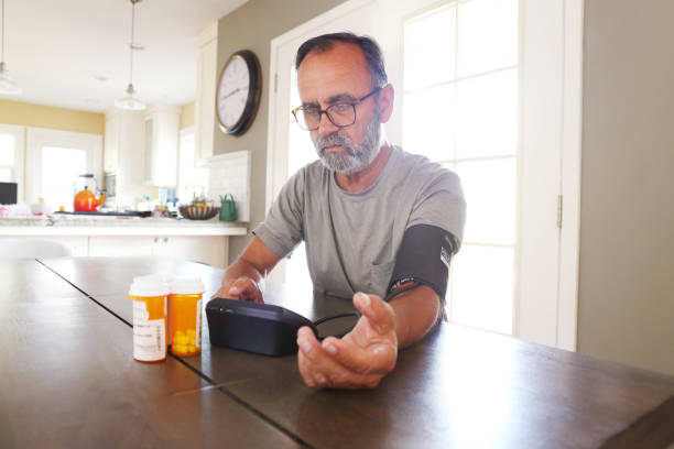istock Latino Man Sitting At Table Checking His Blood Pressure 2163543755