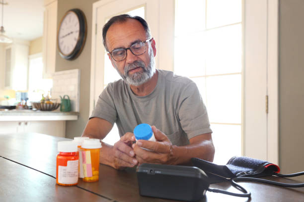 Latino Man Sitting At Table Sorting Through Prescription Medications