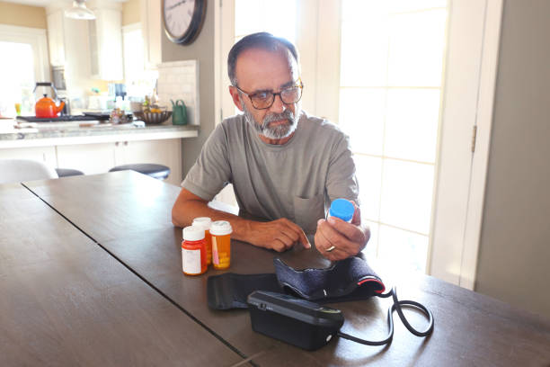 istock Latino Man Sitting At Table Sorting Through Prescription Medications 2163543761