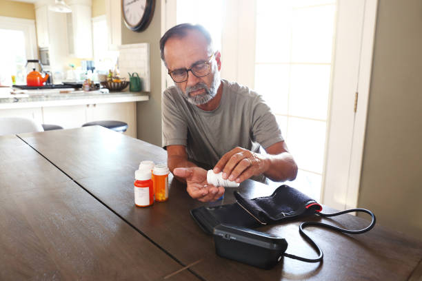 istock Latino Man Sitting At Table Sorting Through Prescription Medications 2163543762