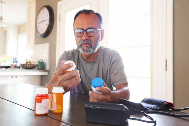 istock Latino Man Sitting At Table Sorting Through Prescription Medications 2163543766