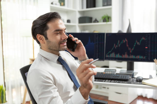 istock Trader calling to consultant or partner with two stock exchange screen. Surmise. 2163549903