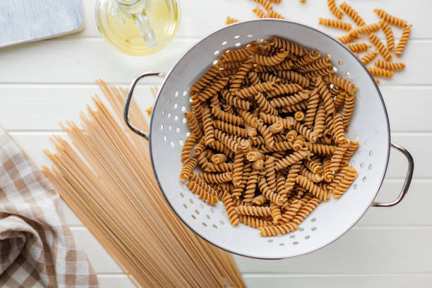 Uncooked whole grain pasta. Raw fusilli in a colander. Top view.
