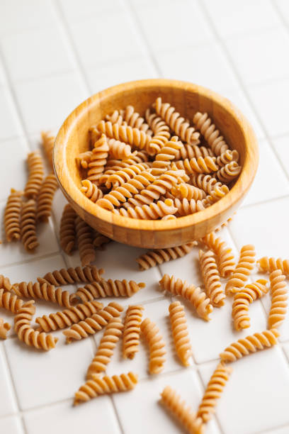 istock Uncooked whole grain pasta. Raw fusilli in bowl. 2163550203