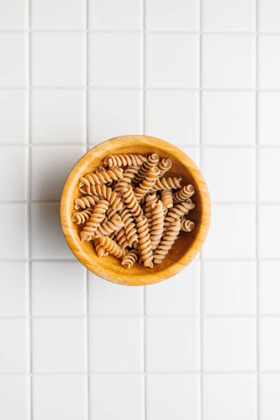 istock Uncooked whole grain pasta. Raw fusilli in bowl. 2163550208