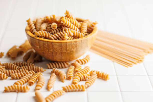 istock Uncooked whole grain pasta. Raw fusilli in bowl. 2163550213