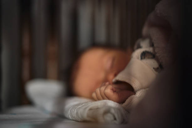 Close-up of a newborn baby girl peacefully sleeping in the crib. Focus on hands.